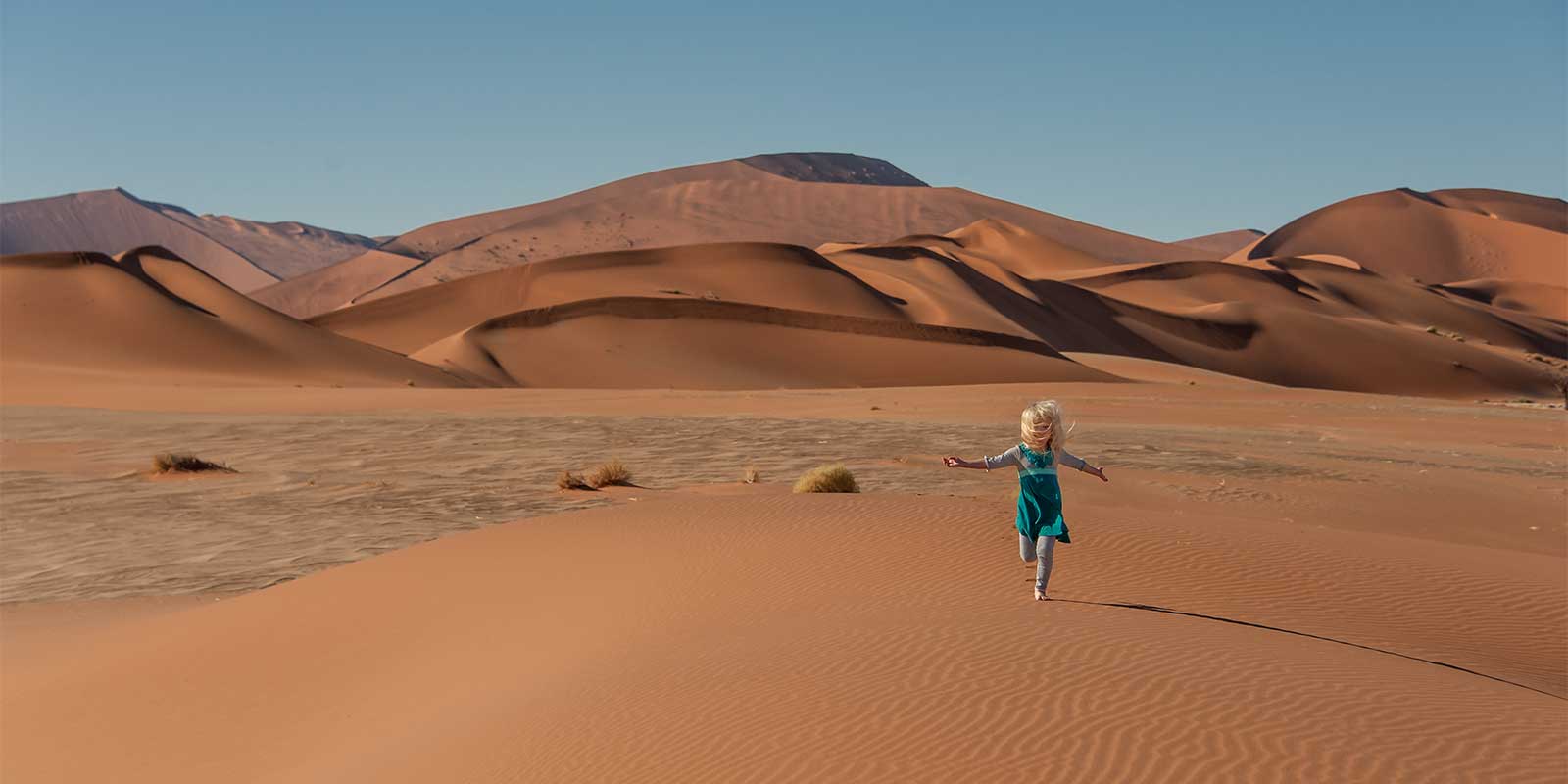 Girl running on a sand dune in the Namib Desert, Namibia