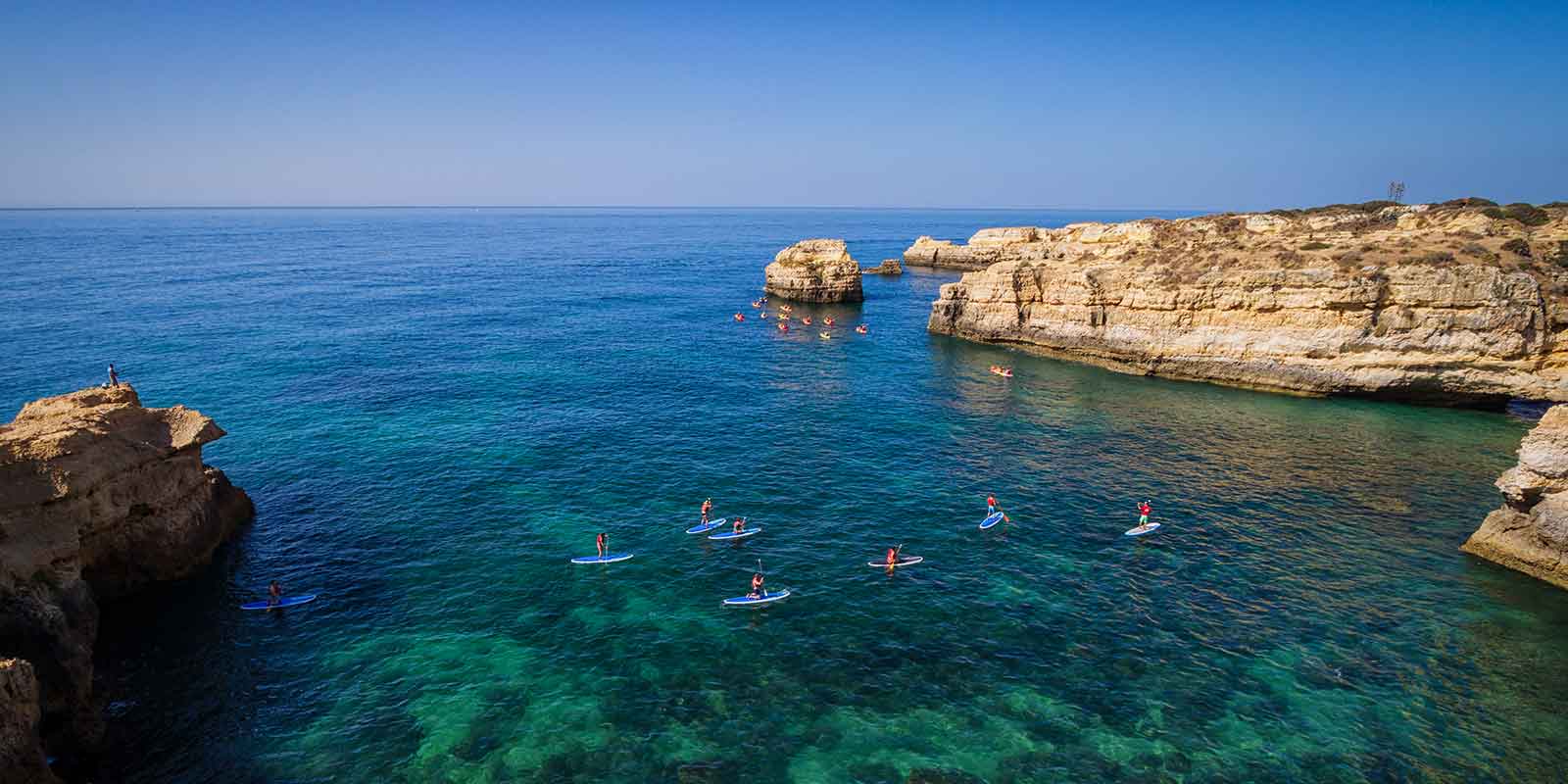 Group of paddleboarders in a secluded bay on the Atlantic coast in the Algarve, Portugal