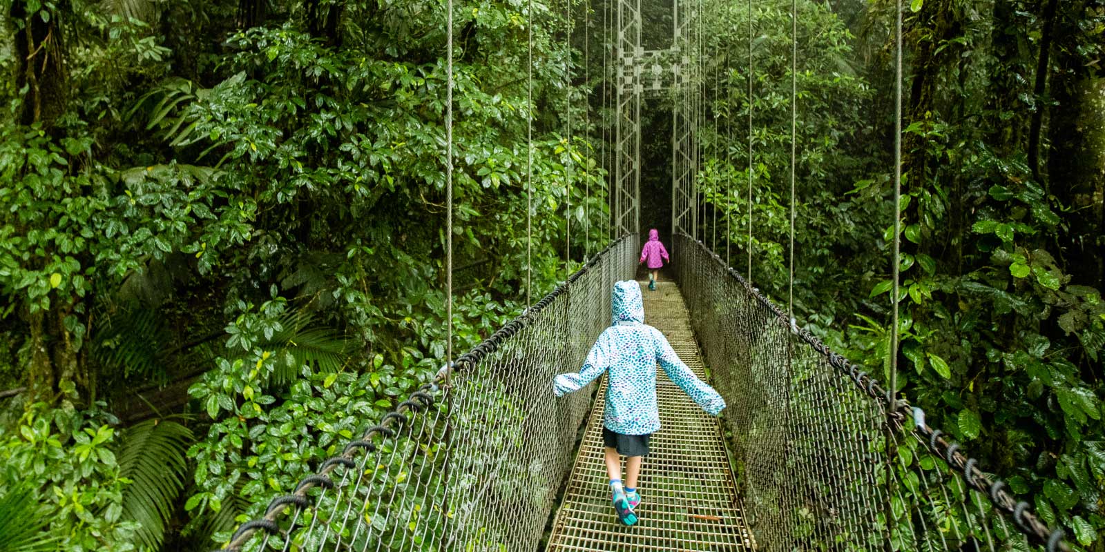 Girls walking across hanging bridge in Costa Rica