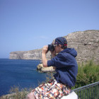 Young boy looking out to sea with binoculars in Gozo, Malta