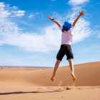 Child jumping in the air on the sand dunes in the Sahara Desert, Morocco