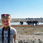 Young girl with elephants at a watering hole behind her in Namibia