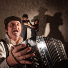 Singer playing accordian, with couple dancing the tango in the background
