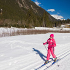 Winter scene of young girl cross country skiing in Norway, surrounded by mountains.