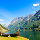 Viking boat in foreground in front of fjord and mountain scenery in Norway
