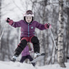 Young girl jumping during skiing lesson in forests of Norway