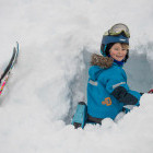Girl digging snow cave during a skiiing trip in Norway