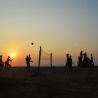 Boys playing beach volleyball at sunset