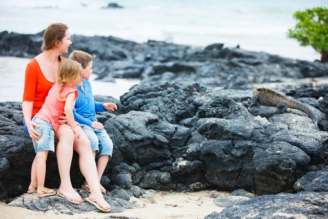 Family watching a marine iguana in the Galapagos Islands
