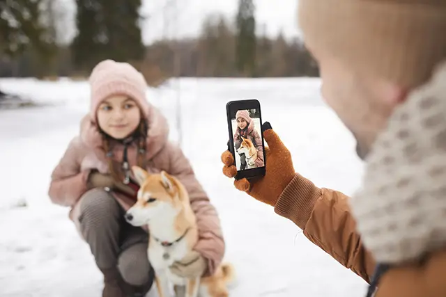 Father taking picture of girl & husky in Finland