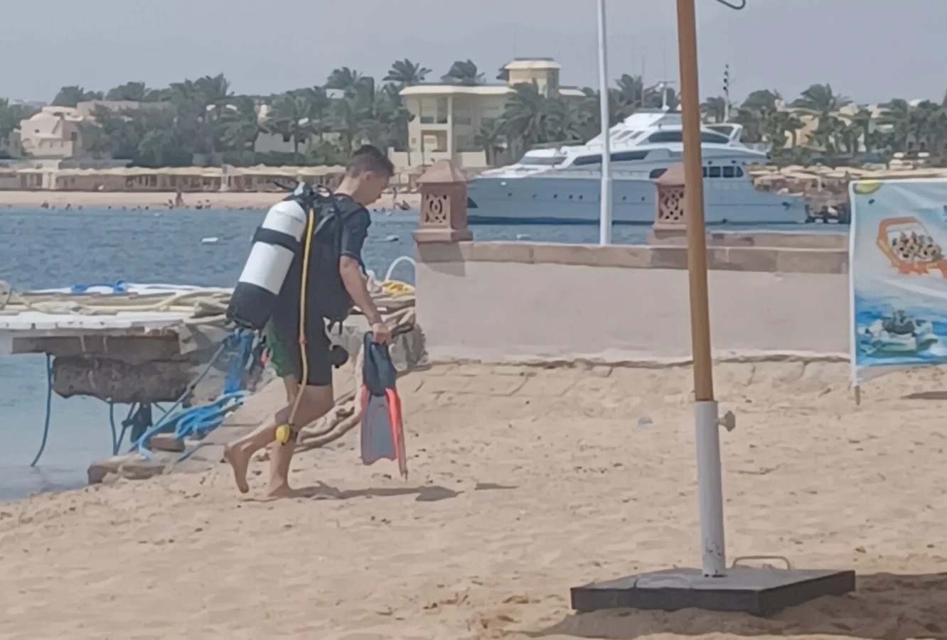 Boy with dive kit on, leaving the shore in Egypt
