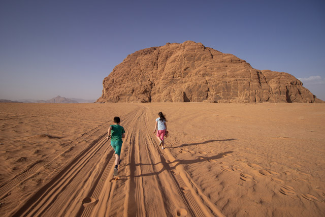 Siblings running through a desert in Wadi Rum, Jordan