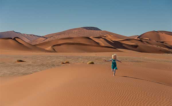 Girl running on a sand dune in the Namib Desert, Namibia