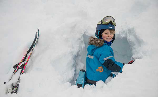 Young girl digging a snow cave during a skiing trip in Norway